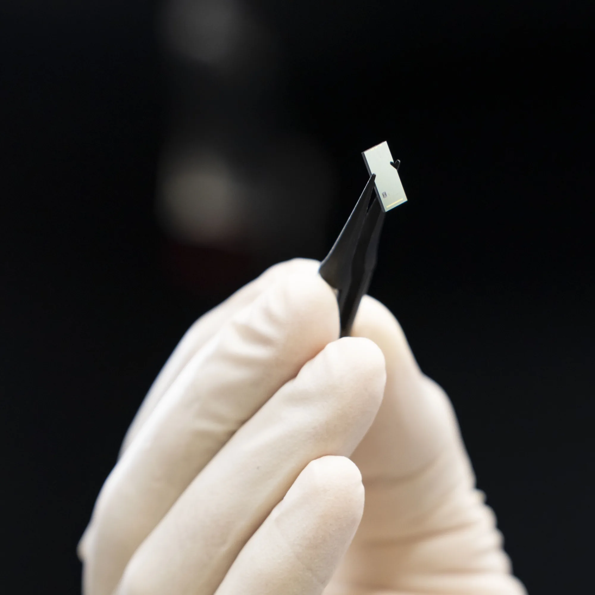 A researcher holds a photonic integrated chip packaged for extreme environments. Photo: M. King / NIST.